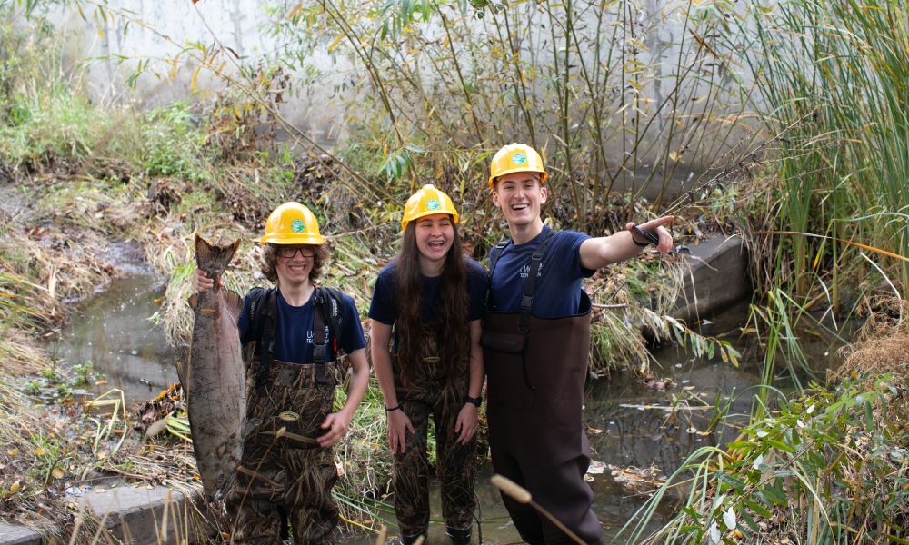 Casa Grande students standing in a river, holding a big fish by the tail