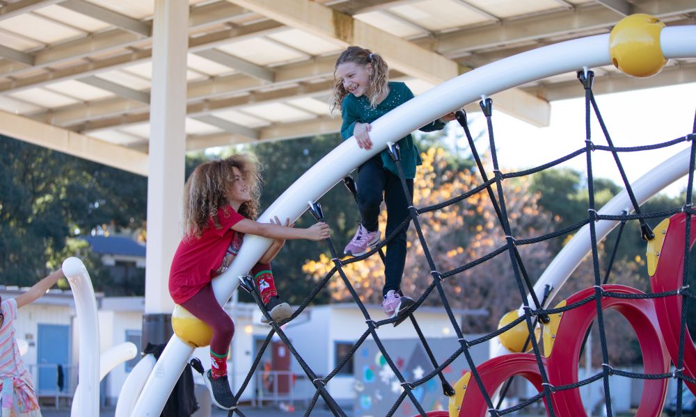 Two children climbing together on a jungle gym