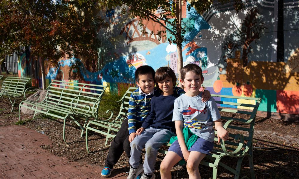 Three Grant Elementary School students sitting together on a metal bench