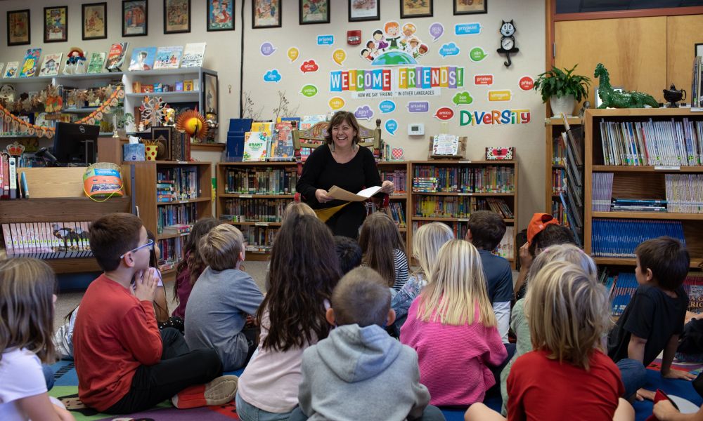 Grant Elementary students sitting on a colorful rug, listening to someone read aloud from a book