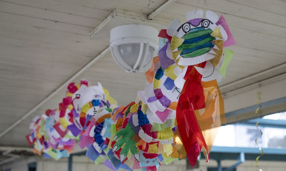 A handmade Chinese dragon created out of colorful paper plates and tissue paper, hanging from the ceiling.