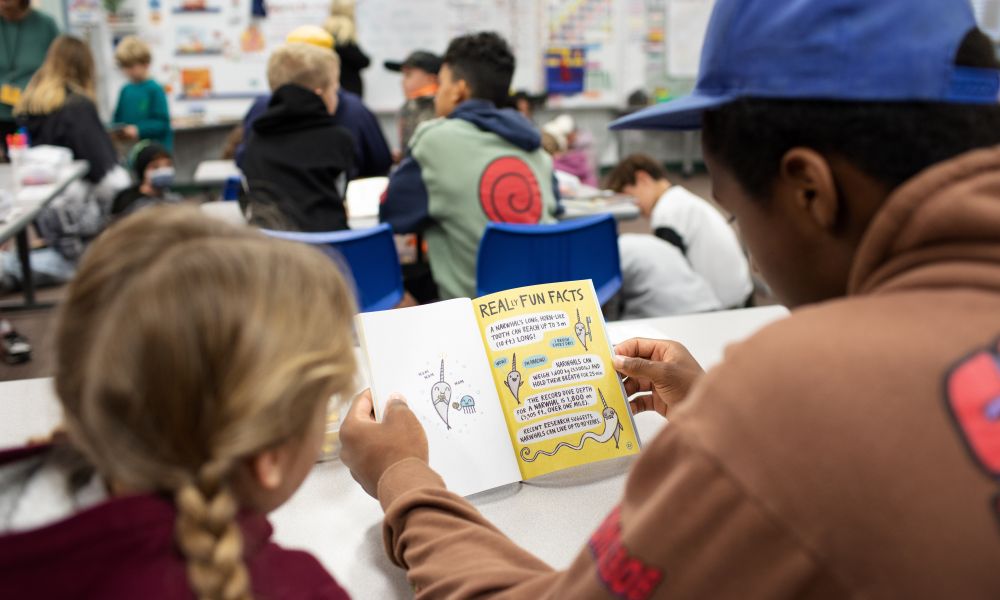 Two students reading a book together at a desk