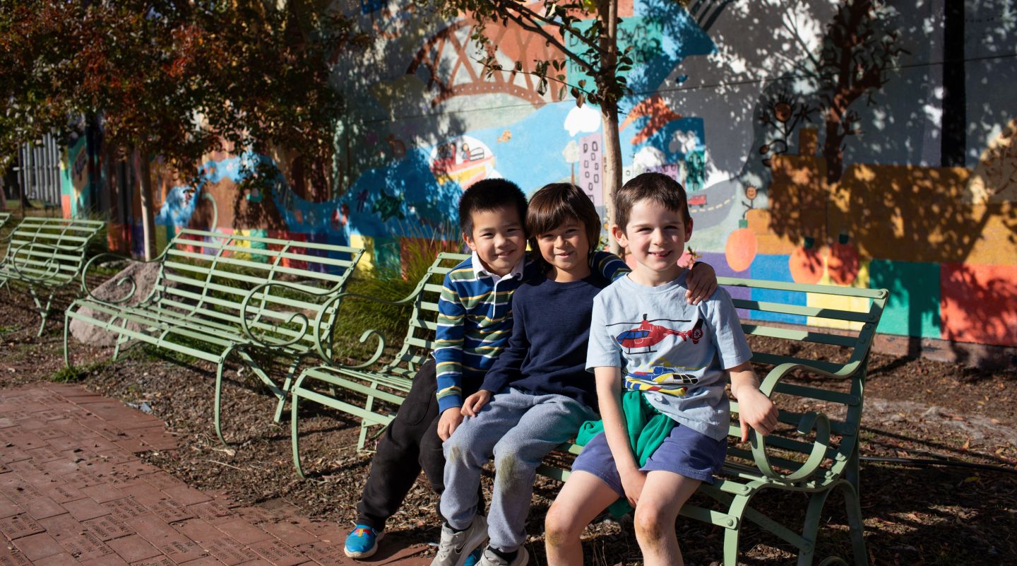 Three Grant Elementary School students sitting together on a metal bench