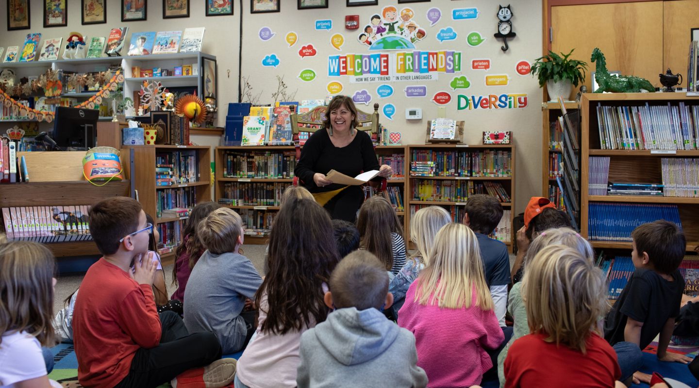 Grant Elementary students sitting on a colorful rug, listening to someone read aloud from a book