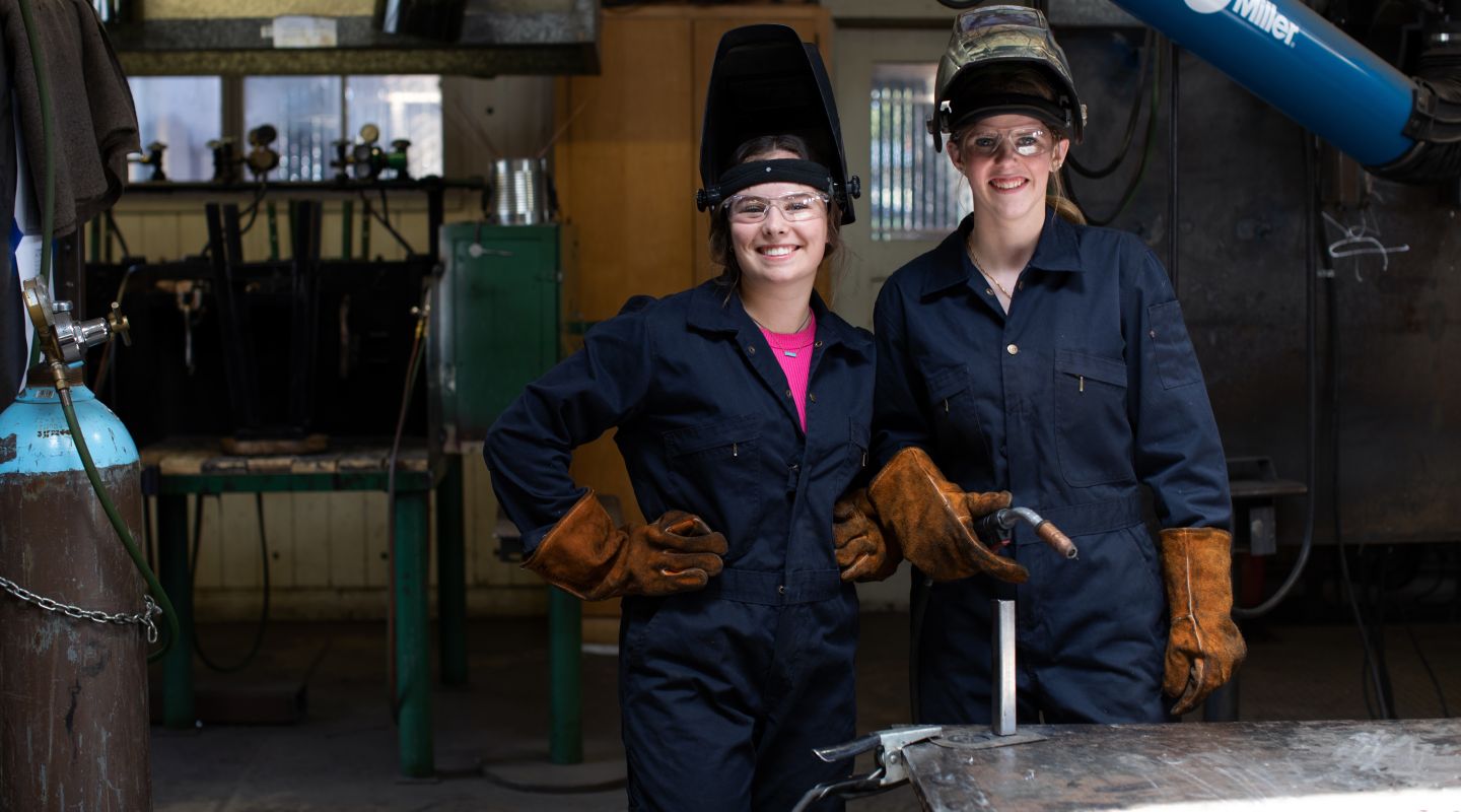 Two PHS Metal Shop students holding and wearing welding supplies