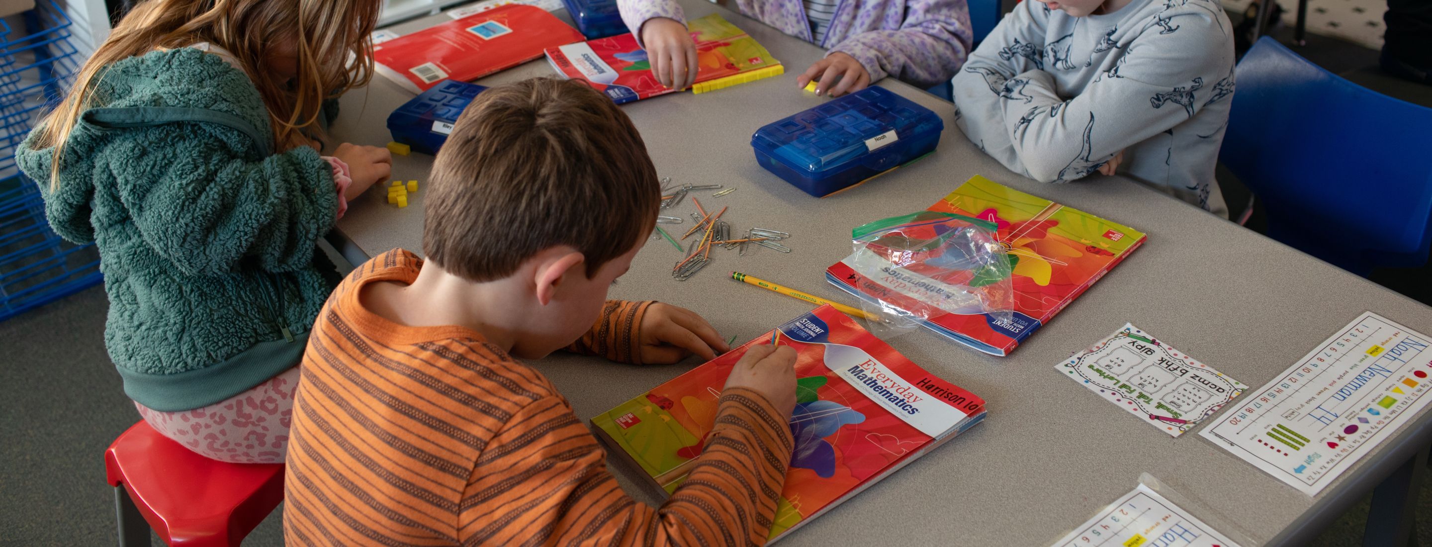 Four Penngrove students sitting at a square table, working with mathematics workbooks.