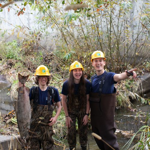 Casa Grande students standing in a river, holding a big fish by the tail